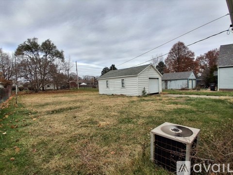 A backyard with a white shed and a grassy area.