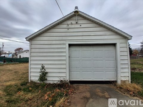 A small white building with a garage door is available for purchase.