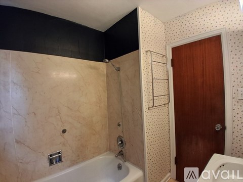 A bathroom with a marble tub and a wooden door.