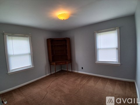A room with a brown chair and a window with blinds.