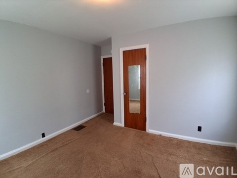 A room with a carpeted floor and a wooden door.