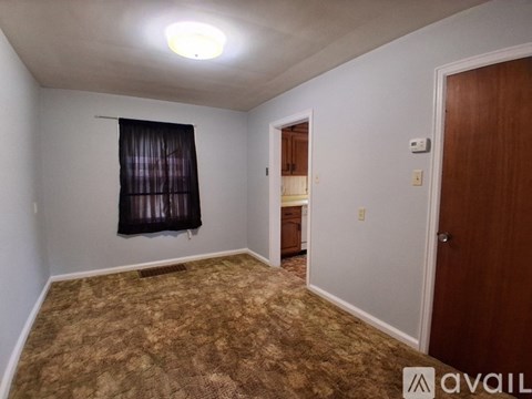 A room with a carpeted floor and a window with a black curtain.