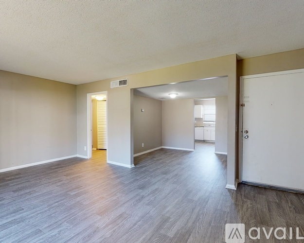 A spacious room with wooden flooring and a white door.