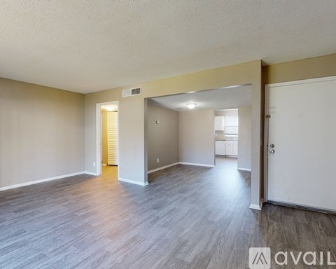 A spacious room with wooden flooring and a white door.