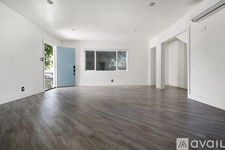 A spacious room with wooden flooring and white walls.