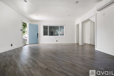 A spacious room with wooden flooring and white walls.