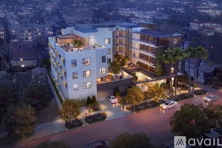 A modern multi-story building with a rooftop terrace is lit up at night.