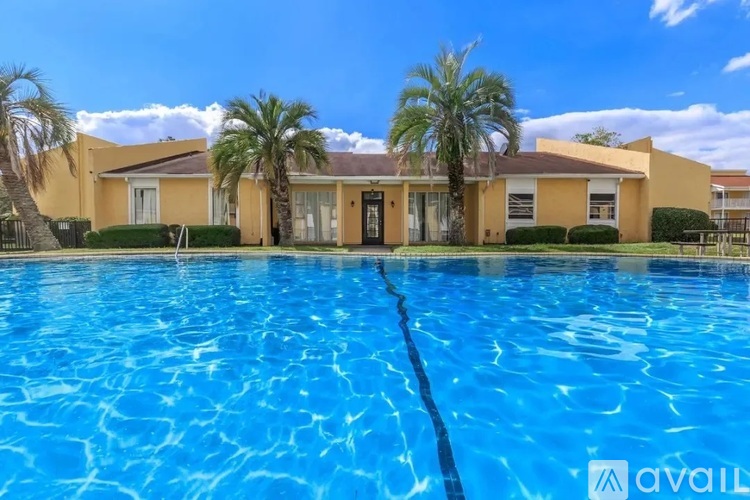 A swimming pool in front of a yellow building with palm trees.