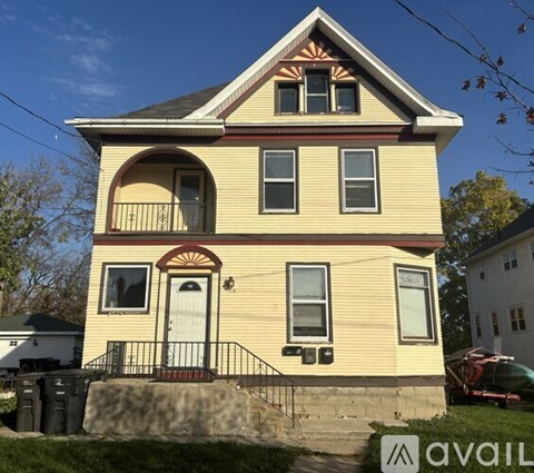 A two-story house with a red door and a balcony.