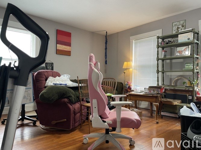 A room with a pink chair, a red chair, and a white desk.