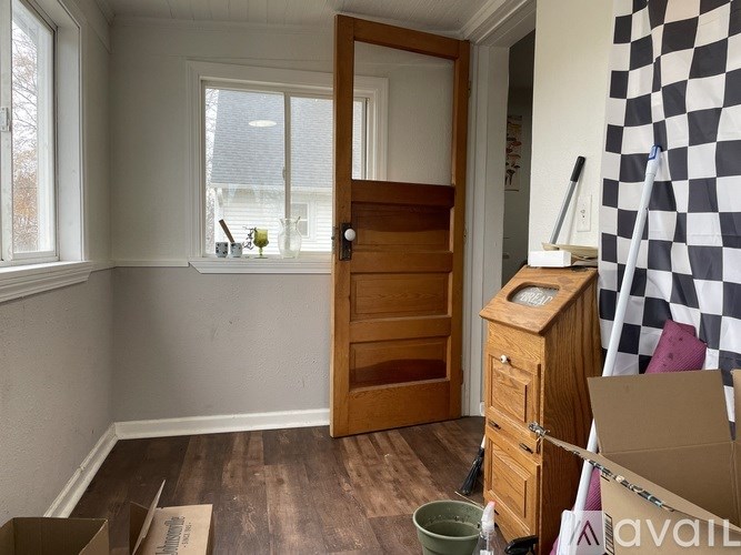 A room with a wooden door and a window with a view of trees outside.