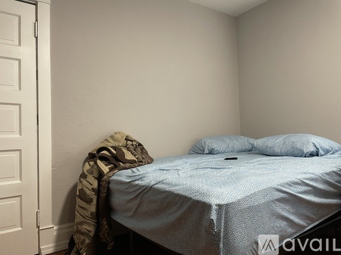 A bed with a blue blanket and two pillows is in a room with a white door.