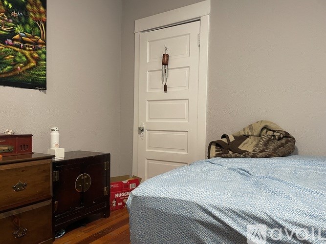 A bedroom with a bed, dresser, and a painting on the wall.