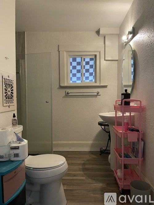 A bathroom with a toilet, sink, and a pink shelf.