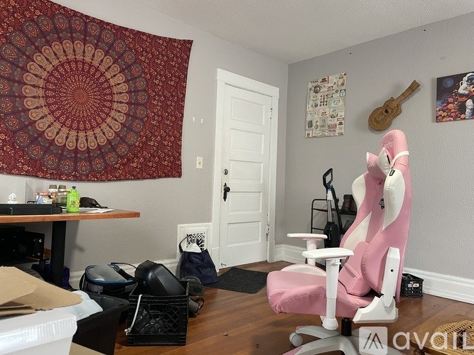 A room with a pink chair and a rug.