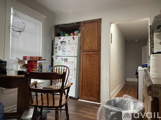 A kitchen with a wooden chair and a white fridge.
