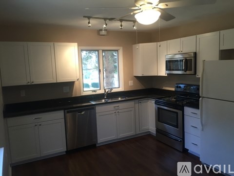 A kitchen with white cabinets and black countertops.