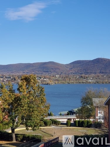 A view of a lake with mountains in the background and a house with a tree in the foreground.