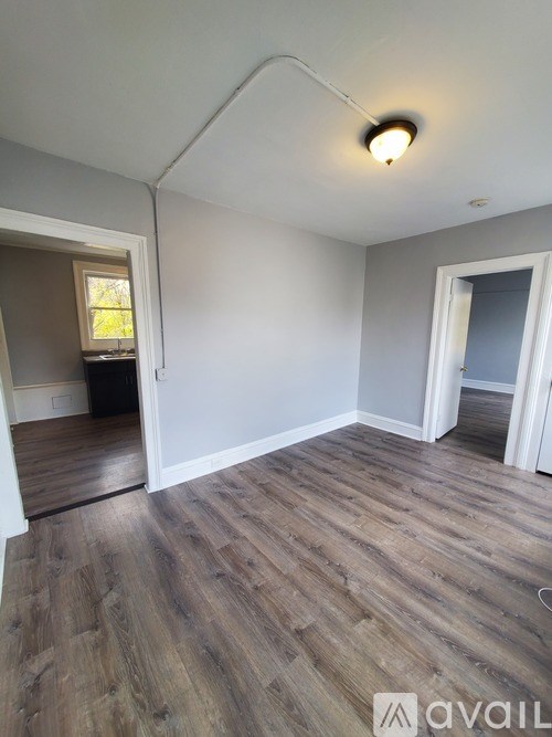 A room with wooden flooring and white walls is available for rent.