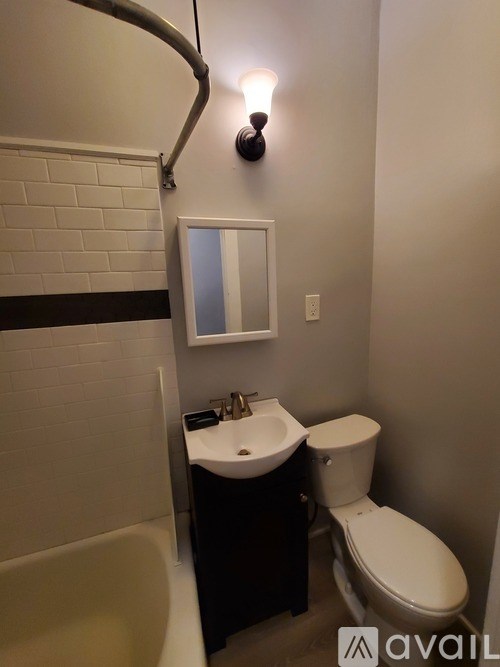 A bathroom with a toilet, sink, and mirror.