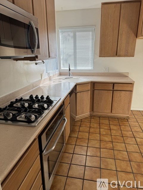 A kitchen with a stove, sink, and cabinets.
