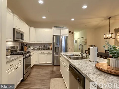 A kitchen with white cabinets and a stainless steel refrigerator.