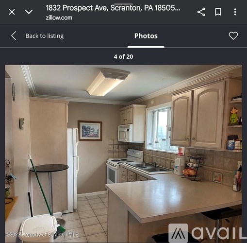 A kitchen with a refrigerator, sink, and a dining table.