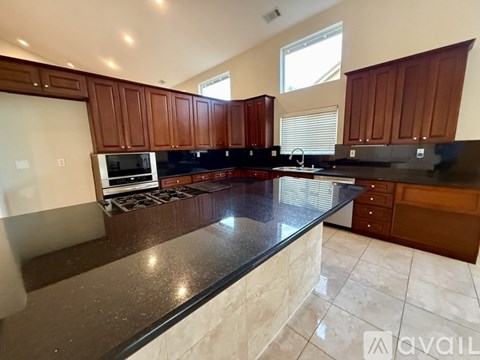 A kitchen with dark brown cabinets and a black countertop.