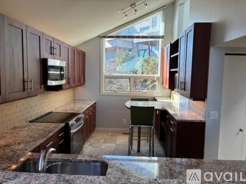 A kitchen with dark wood cabinets and granite countertops.