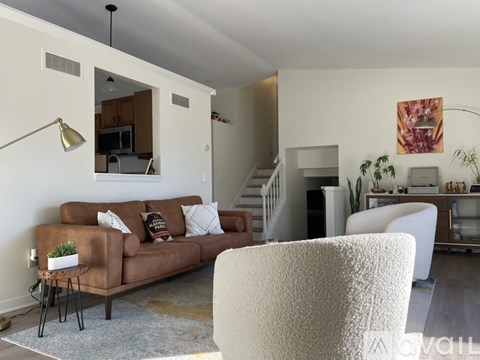 A living room with a brown couch and a white chair.