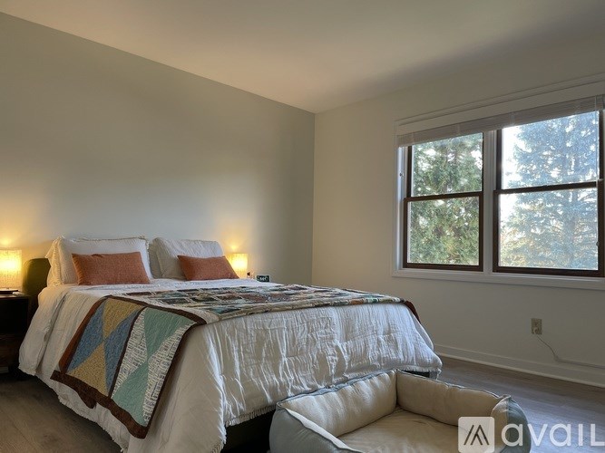 A bedroom with a bed and a window overlooking trees.