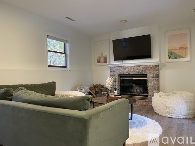 A living room with a green couch, a fireplace, and a television mounted on the wall.