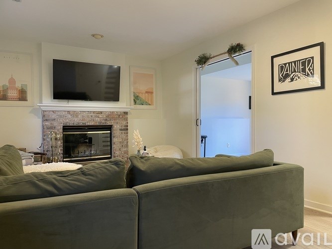A living room with a grey couch, a fireplace, and a flat screen TV mounted above it.
