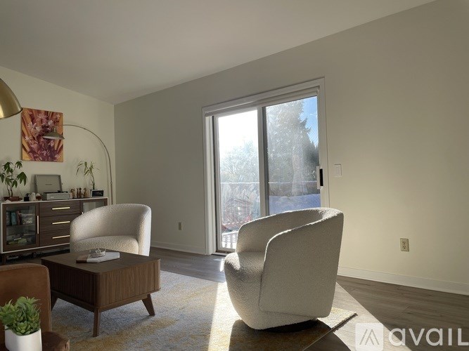A living room with a brown coffee table and two white chairs.