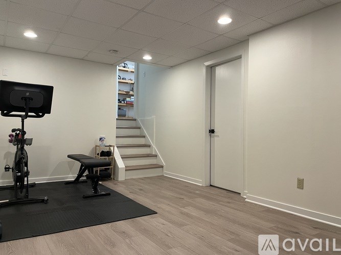A room with a black exercise bike and a staircase in the background.