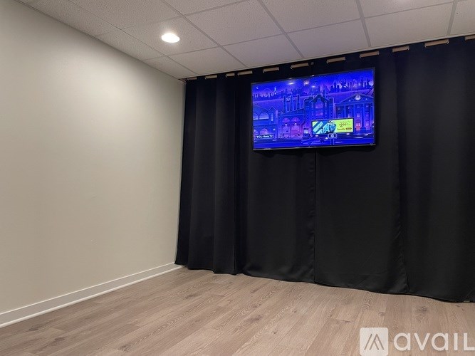 A room with a television on the wall and a black curtain.