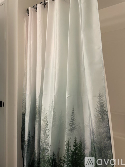 A white shower curtain with a forest scene printed on it.