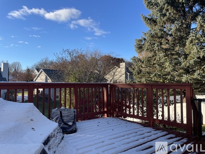A snow-covered deck with a red railing and a backpack on it.
