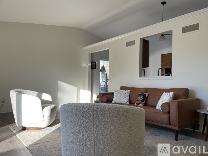 A living room with a brown couch and a white chair.