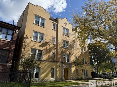 A yellow building with a black fence in front.