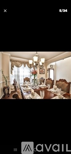A well-lit dining room with a chandelier and a table set for a meal.