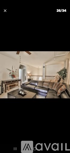 A modern living room with a dark leather couch and a wooden coffee table.