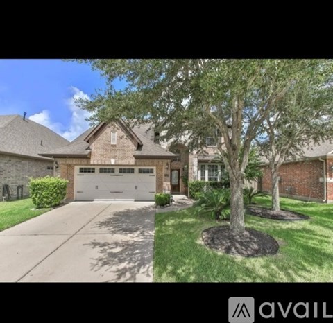A house with a tree in front and a driveway leading to a garage.