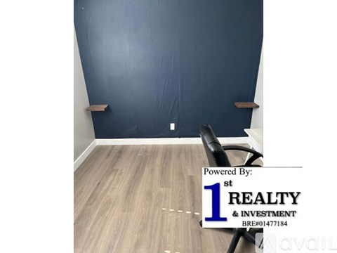 A room with a dark blue wall and light wooden floor.