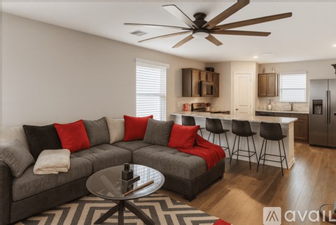 A modern living room with a grey sofa and a round glass table.