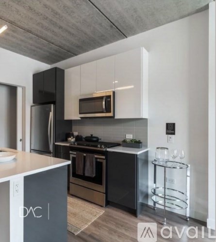 A modern kitchen with a black refrigerator and stove, and a white countertop.