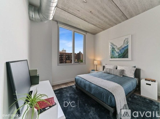 A bedroom with a bed, a desk, and a window overlooking a cityscape.