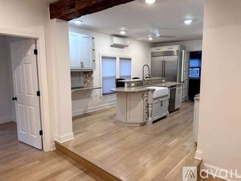A kitchen with white cabinets and a wooden floor.