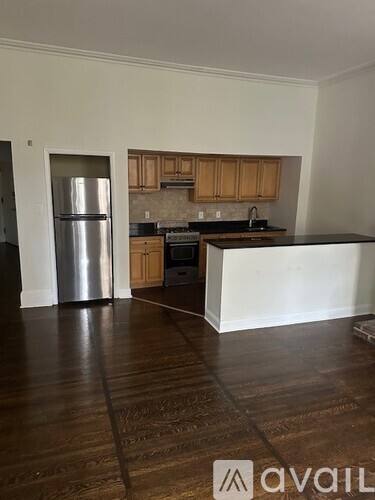 A kitchen with wooden cabinets and a stainless steel refrigerator.