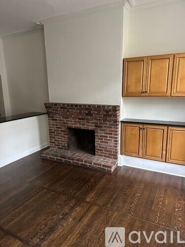 A room with a brick fireplace and wooden cabinets.